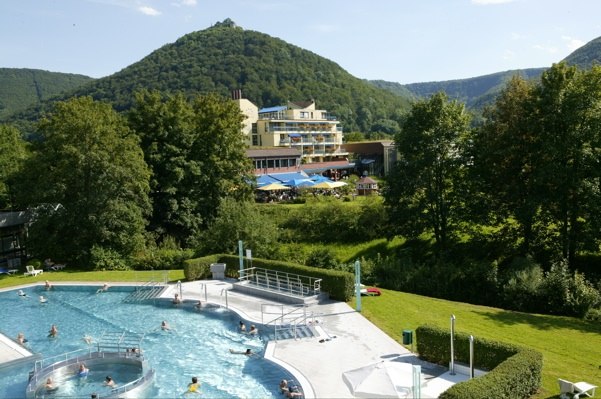 Hotel with pool in front of wooded hills, surrounded by green landscape and trees, under a blue sky., © ©hotel-graf-eberhard.de Hotel with pool in front of wooded hills, surrounded by green landscape and trees, under a blue sky., © ©hotel-graf-eberhard.de