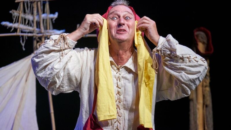 An actor in a historical costume holds a yellow headdress and makes an expressive gesture on stage., &copy; Theaterhaus Stuttgart e.V.