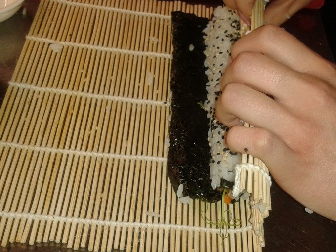 Eine Person rollt Sushi mit einer Bambusmatte. Reis und Nori-Blatt sind sichtbar. Hände halten die Matte fest., © Kultweine-Kochwelten-Kunstücke - Kochschule Sonja Lenz Eine Person rollt Sushi mit einer Bambusmatte. Reis und Nori-Blatt sind sichtbar. Hände halten die Matte fest., © Kultweine-Kochwelten-Kunstücke - Kochschule Sonja Lenz