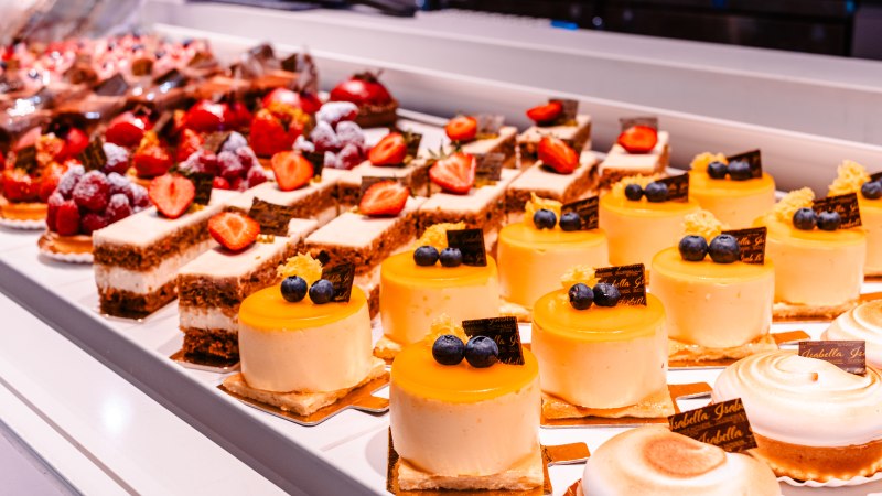 Vitrine mit verschiedenen Kuchen und Torten, darunter gelbe Törtchen mit Heidelbeeren und Erdbeerkuchen., © Sarah Schmid Vitrine mit verschiedenen Kuchen und Torten, darunter gelbe Törtchen mit Heidelbeeren und Erdbeerkuchen., © Sarah Schmid