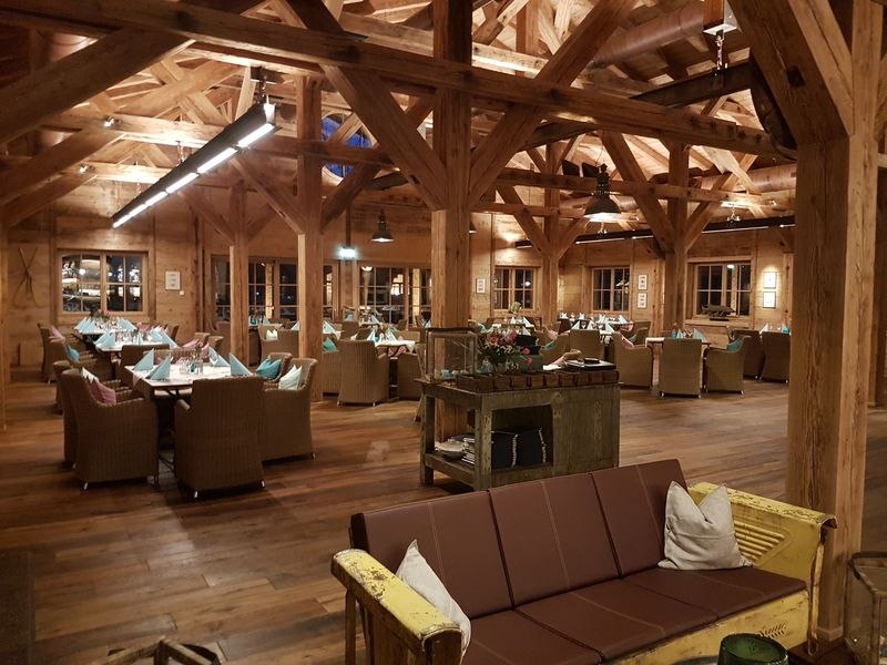 Rustic restaurant with wooden beams, covered tables and cozy seating in warm light., © TOMAS