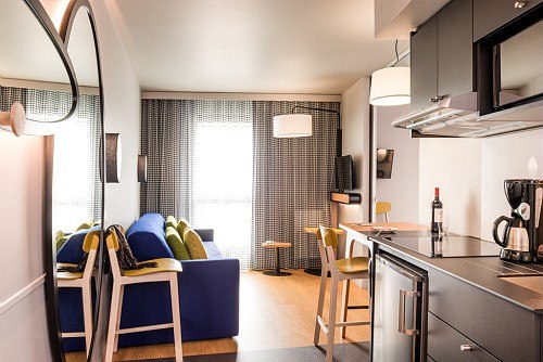 Modern studio with kitchen, sofa, dining table and large windows. Bright, stylish furnishings with bottles of wine and coffee machine on the counter., &copy; adagio access Stuttgart Airport Messe
