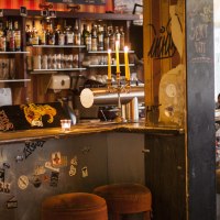 A cozy bar with skateboard decor on the counter, candlesticks and bar stools. Bottles and glasses can be seen in the background., © Mata Hari, Stuttgart A cozy bar with skateboard decor on the counter, candlesticks and bar stools. Bottles and glasses can be seen in the background., © Mata Hari, Stuttgart