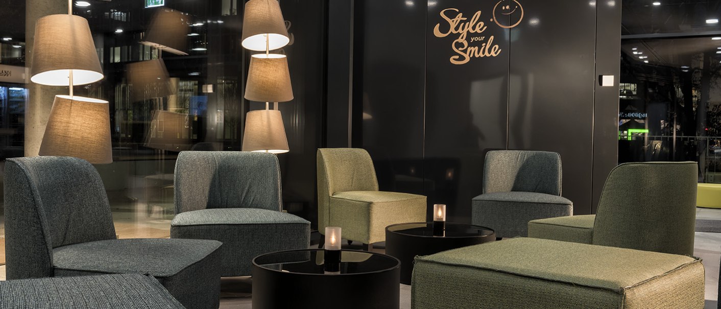 Moderne Lobby mit bequemen Sesseln, runden Tischen und stilvollen Stehlampen. An der Wand steht "Style your Smile". Gemütliche Atmosphäre., © ibis Styles Stuttgart Vaihingen Moderne Lobby mit bequemen Sesseln, runden Tischen und stilvollen Stehlampen. An der Wand steht "Style your Smile". Gemütliche Atmosphäre., © ibis Styles Stuttgart Vaihingen