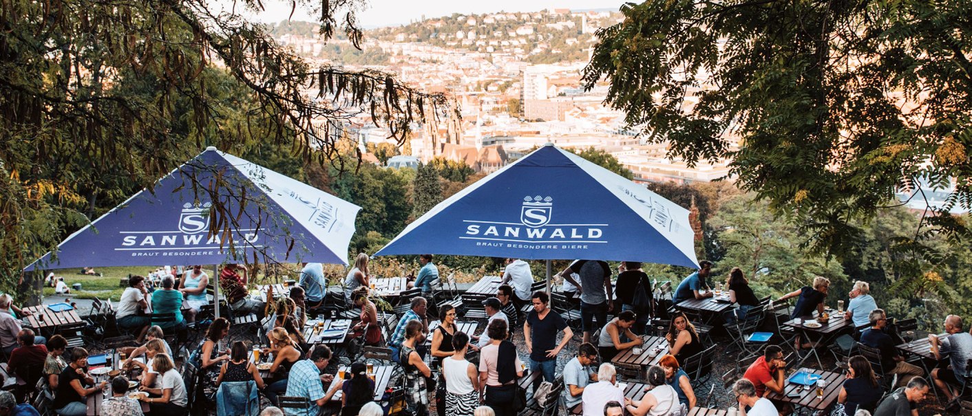 Beer garden on the Karlsh&ouml;he in Stuttgart with many people under blue parasols, the city view in the background., &copy; Romeo Felsenreich, sommertage.com