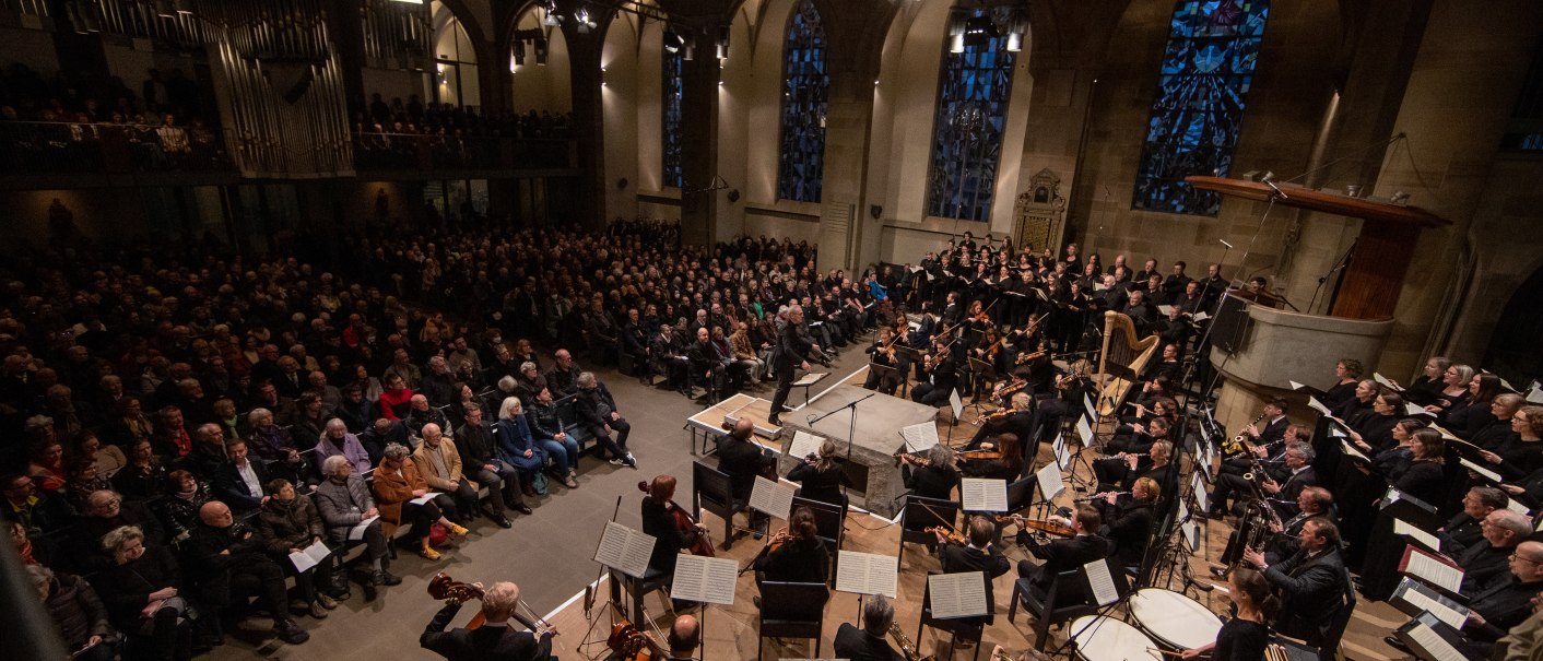 An orchestra and choir perform in a church in front of a large audience. The church has high windows and an organ., © www.hassfoto.de
