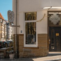 Eingang des Caf&eacute; Seyffer&rsquo;s an einer Stra&szlig;enecke, dekoriert mit goldenen Girlanden und Pflanzen. Die Stra&szlig;e ist von Wohnh&auml;usern ges&auml;umt., &copy; SMG, Sarah Schmid