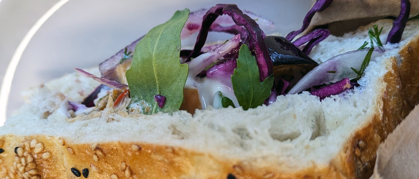 Close-up of a kebab with sesame bread, red cabbage, rocket and sauce. Fresh ingredients are visible., © SMG
