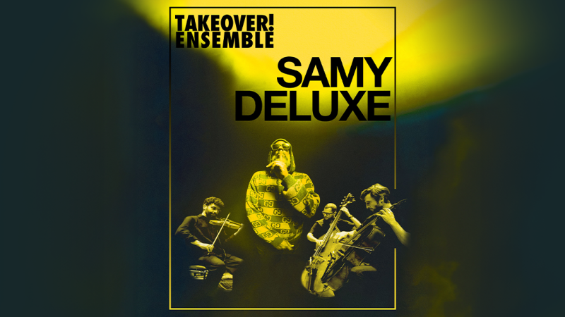 Samy Deluxe performt mit dem Takeover! Ensemble. Er steht im Mittelpunkt, umgeben von Musikern mit Streichinstrumenten, in gelbem B&uuml;hnenlicht., &copy; links im Bild