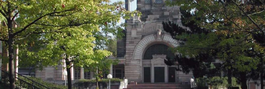 Ein historisches Krematoriumsgeb&auml;ude mit markanter Architektur, umgeben von gr&uuml;nen B&auml;umen und einem gepflasterten Weg im Vordergrund., &copy; SMG