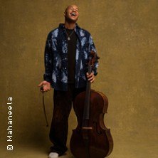 Ein Musiker steht lachend mit einem Cello vor einem neutralen Hintergrund. Er trägt eine gemusterte Jacke und hält den Bogen in der Hand., © links im Bild Ein Musiker steht lachend mit einem Cello vor einem neutralen Hintergrund. Er trägt eine gemusterte Jacke und hält den Bogen in der Hand., © links im Bild