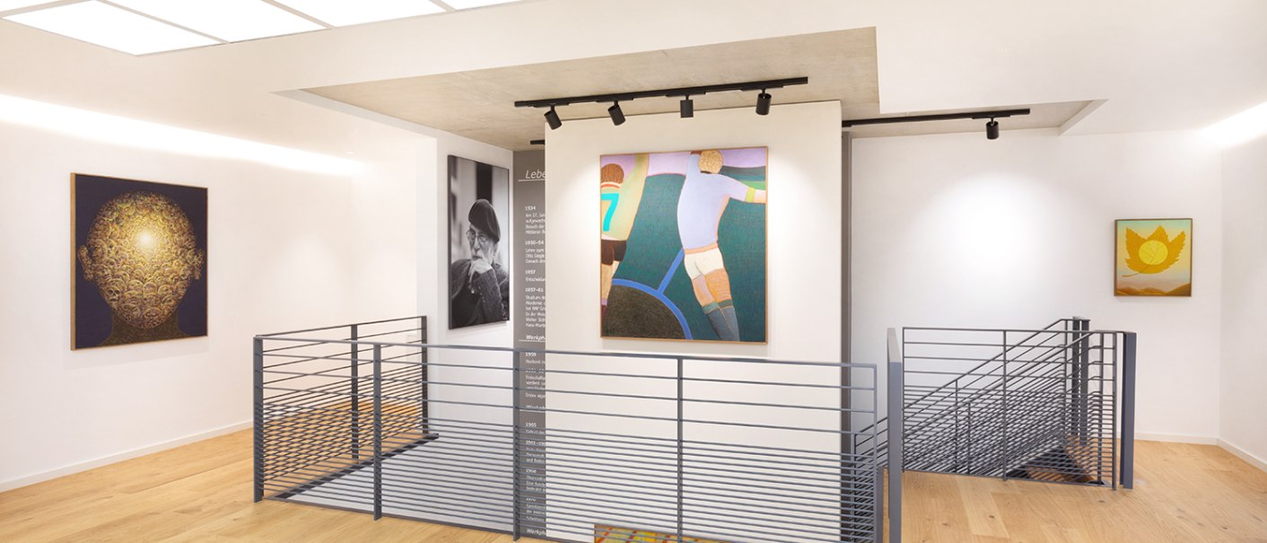 A modern gallery with wooden floors, paintings on white walls, and a central stair railing. Bright lighting and a minimalist design., © Freundeskreis Fritz Genkinger e.V. A modern gallery with wooden floors, paintings on white walls, and a central stair railing. Bright lighting and a minimalist design., © Freundeskreis Fritz Genkinger e.V.