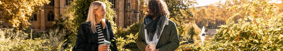 Two people are talking in front of St. John's Church on the Feuersee, surrounded by autumn leaves and sunshine., &copy; SMG, Sarah Schmid