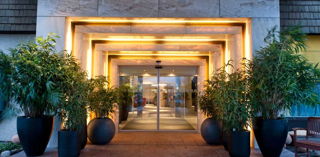 The entrance to the Wyndham Stuttgart Airport Messe Hotel has a modern design with large plants and stylish lighting., © Wyndham Stuttgart Airport Messe The entrance to the Wyndham Stuttgart Airport Messe Hotel has a modern design with large plants and stylish lighting., © Wyndham Stuttgart Airport Messe