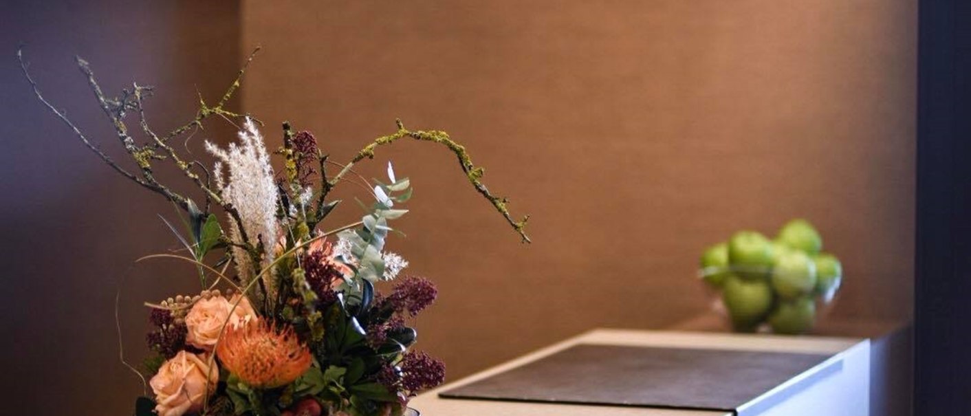 Elegant reception with flower arrangement and modern hanging lamps. A bowl of green apples in the background., © TOMAS Elegant reception with flower arrangement and modern hanging lamps. A bowl of green apples in the background., © TOMAS