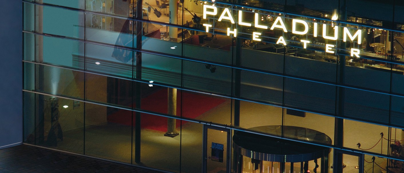Nachtaufnahme des beleuchteten Eingangs des Palladium Theaters mit Glasfassade und rotem Teppich., &copy; Stage Entertainment