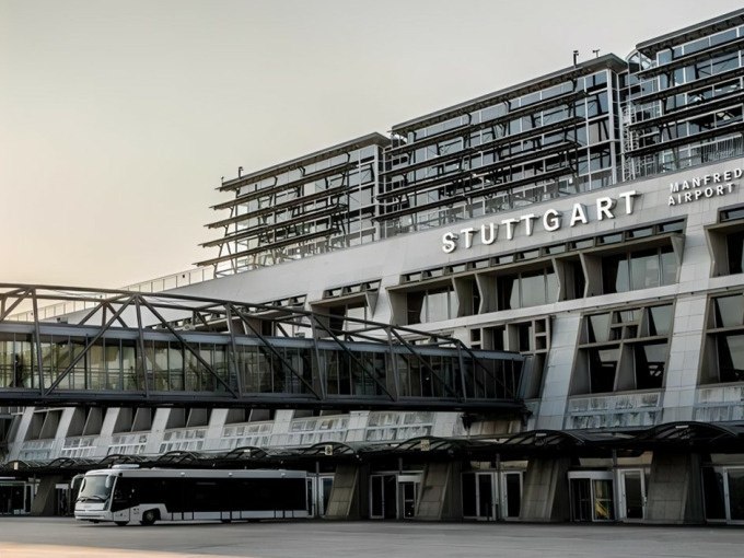 Außenansicht des Stuttgarter Flughafens mit moderner Architektur und einem Bus im Vordergrund., © Schlienz-Tours GmbH & Co.KG Außenansicht des Stuttgarter Flughafens mit moderner Architektur und einem Bus im Vordergrund., © Schlienz-Tours GmbH & Co.KG