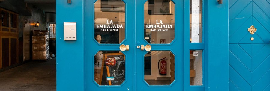 Gro&szlig;e Doppelt&uuml;r in leuchtendem Blau mit Glaseins&auml;tzen, auf denen "La Embajada Bar Lounge" in wei&szlig;en Lettern geschrieben steht., &copy; SMG Stuttgart Marketing GmbH - Sarah Schmid