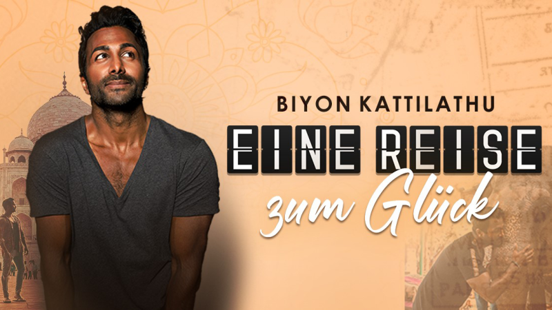 Ein Mann steht vor einem Hintergrund mit dem Taj Mahal. Der Text 'Biyon Kattilathu - Eine Reise zum Gl&uuml;ck' ist prominent zu sehen., &copy; links im Bild