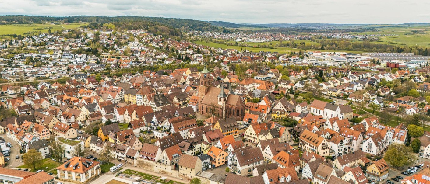 Aerial view of Weil der Stadt with a central church and surrounding houses. The landscape is surrounded by green hills., © Stuttgart-Marketing GmbH, Sarah Schmid