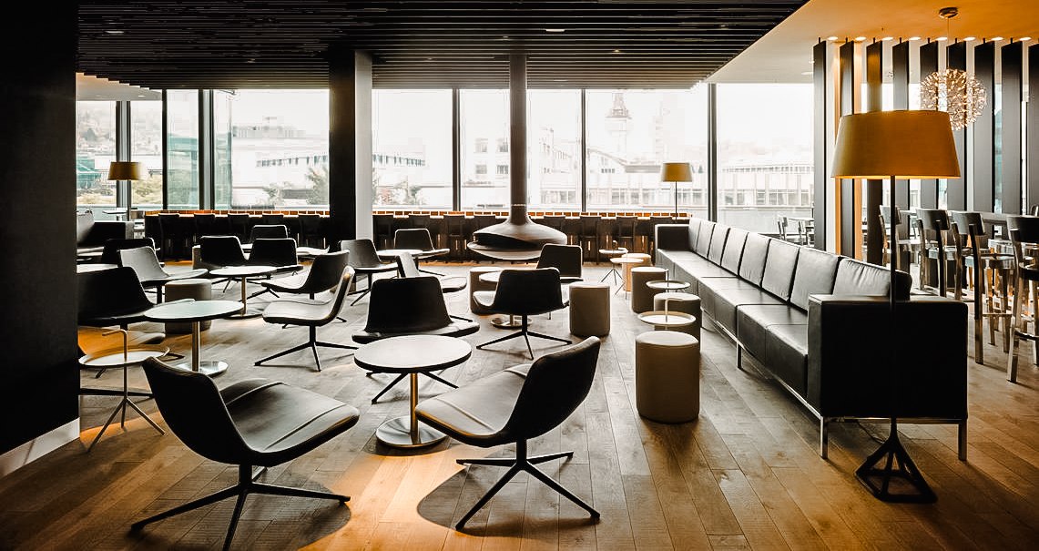 Ein modernes Café mit stilvollen Sesseln, Tischen und großen Fenstern, die viel Licht hereinlassen. Elegante Beleuchtung und Holzboden., © Breuninger