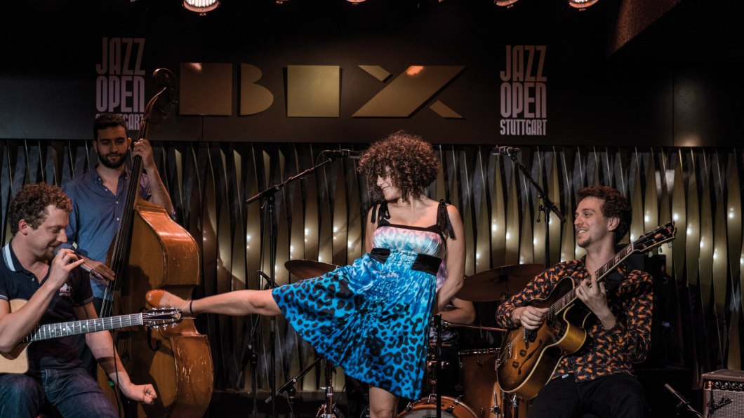 Eine Band spielt im BIX Jazzclub. Ein Gitarrist, ein Kontrabassist und eine Sängerin in blauem Kleid sind zu sehen. "Jazz Open Stuttgart" im Hintergrund., © Peter Steinheisser Eine Band spielt im BIX Jazzclub. Ein Gitarrist, ein Kontrabassist und eine Sängerin in blauem Kleid sind zu sehen. "Jazz Open Stuttgart" im Hintergrund., © Peter Steinheisser