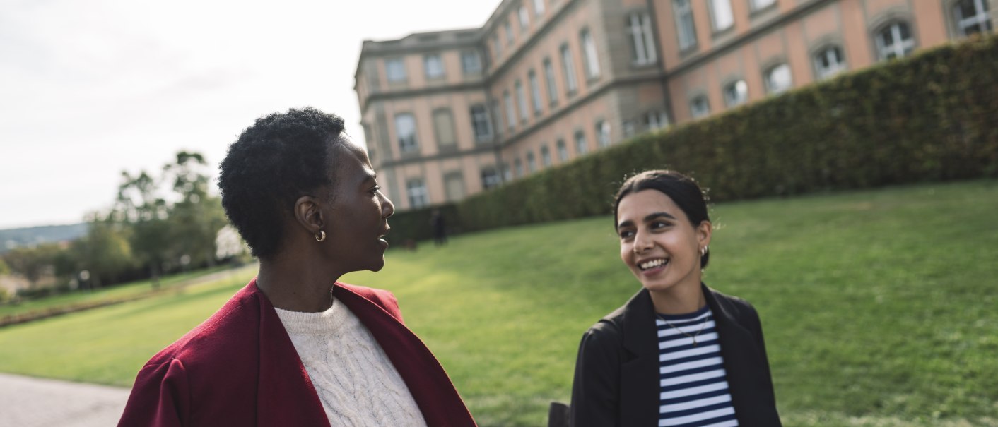 Zwei Personen spazieren und unterhalten sich vor einem historischen Geb&auml;ude mit gepflegtem Rasen im Hintergrund., &copy; Stuttgart-Marketing GmbH, wpsteinheisser