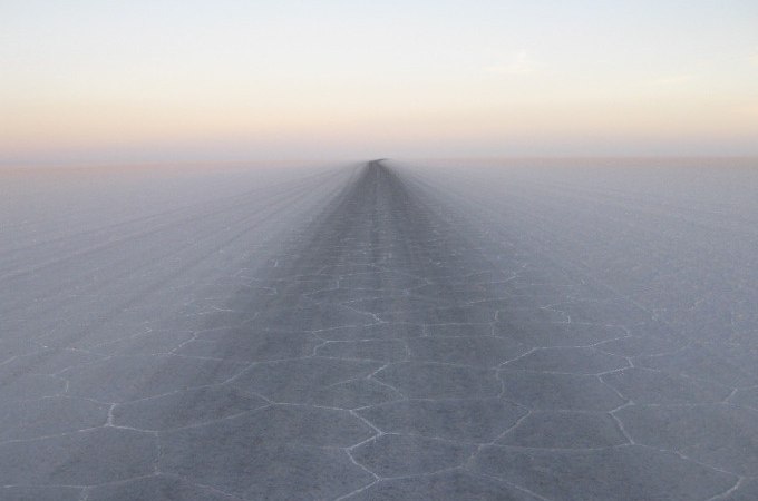 Eine weite Salzebene mit hexagonalen Mustern erstreckt sich bis zum Horizont unter einem klaren Himmel., &copy; Landesmuseum W&uuml;rttemberg