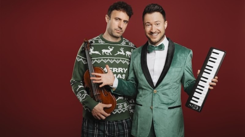 Zwei Männer posieren vor einem roten Hintergrund. Einer trägt einen Weihnachtspullover und hält eine Geige, der andere trägt einen grünen Anzug und hält ein Keyboard., © Renitenztheater Stuttgart e.V. Zwei Männer posieren vor einem roten Hintergrund. Einer trägt einen Weihnachtspullover und hält eine Geige, der andere trägt einen grünen Anzug und hält ein Keyboard., © Renitenztheater Stuttgart e.V.