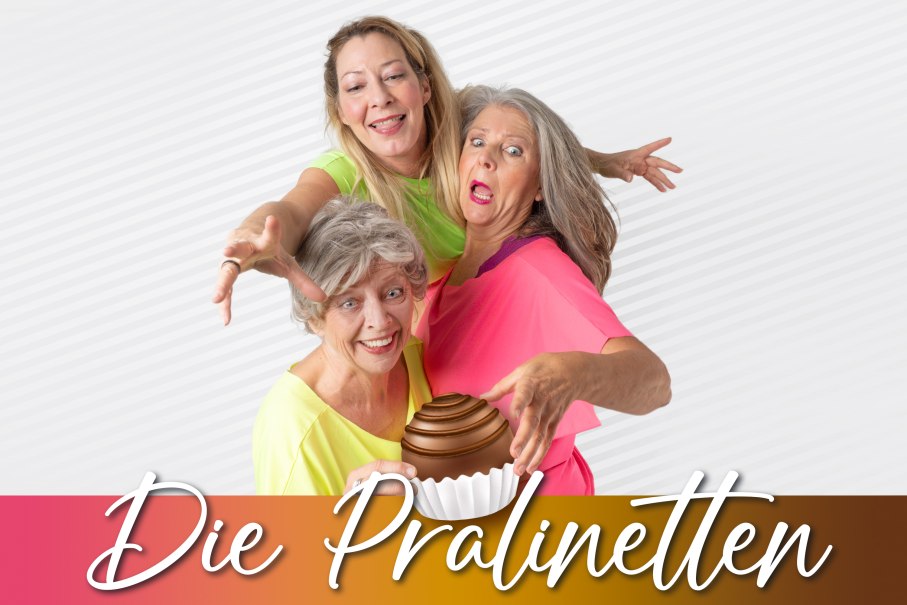 Drei Frauen in bunten Oberteilen posieren fröhlich vor einem gestreiften Hintergrund. Der Schriftzug 'Die Pralinetten' ist am unteren Rand zu sehen., © Friedrichsbau Varieté Drei Frauen in bunten Oberteilen posieren fröhlich vor einem gestreiften Hintergrund. Der Schriftzug 'Die Pralinetten' ist am unteren Rand zu sehen., © Friedrichsbau Varieté