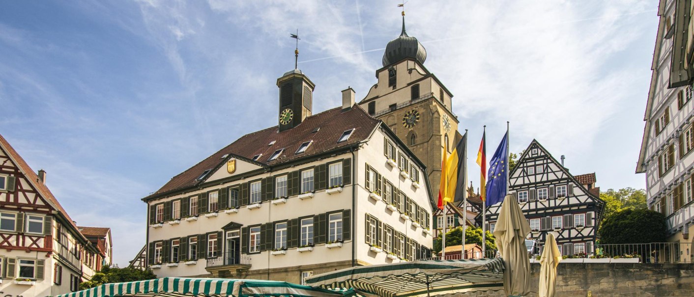 The town square in Herrenberg features the historic town hall and half-timbered houses under a clear sky. Flags are fluttering in the wind., © SMG Stuttgart Marketing GmbH - Sarah Schmid The town square in Herrenberg features the historic town hall and half-timbered houses under a clear sky. Flags are fluttering in the wind., © SMG Stuttgart Marketing GmbH - Sarah Schmid