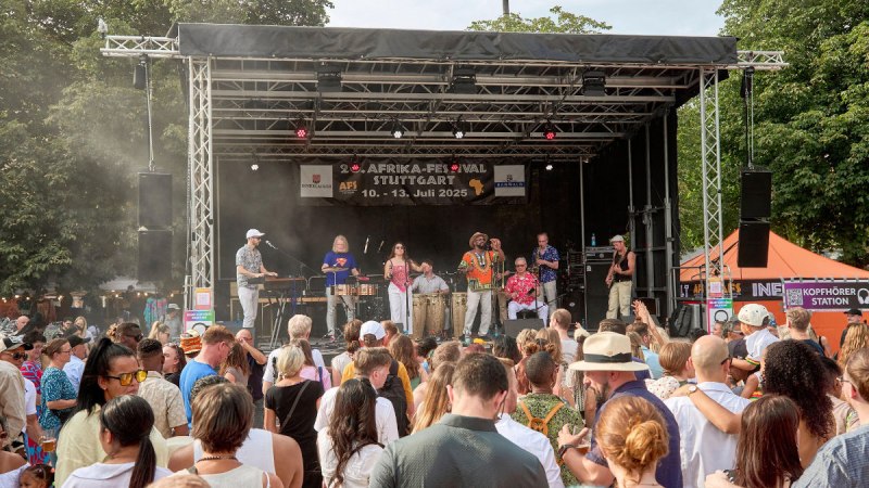 Eine Band spielt auf der B&uuml;hne des Afrika-Festivals Stuttgart 2025. Vor der B&uuml;hne tanzt eine gro&szlig;e Menschenmenge., &copy; Afrika-Festival Stuttgart e.V.