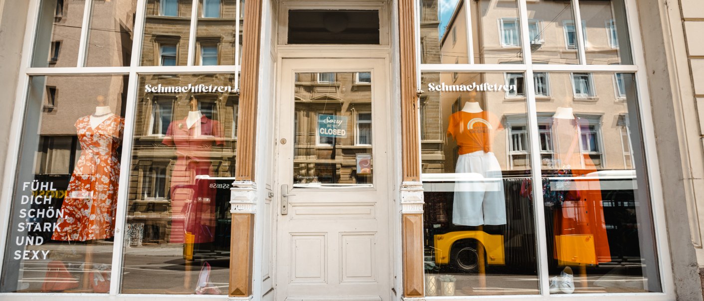 Schaufenster eines Modegeschäfts namens 'Schmachtfetzen' mit bunten Kleidern und einem Schild 'Sorry, we are closed' an der Tür., © SMG Stuttgart Marketing GmbH - Sarah Schmid Schaufenster eines Modegeschäfts namens 'Schmachtfetzen' mit bunten Kleidern und einem Schild 'Sorry, we are closed' an der Tür., © SMG Stuttgart Marketing GmbH - Sarah Schmid