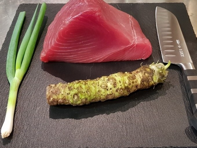 Thunfisch, Wasabi-Wurzel und Fr&uuml;hlingszwiebel auf schwarzer Platte mit Messer, bereit f&uuml;r Sushi-Zubereitung., &copy; Kultweine-Kochwelten-Kunst&uuml;cke - Kochschule Sonja Lenz