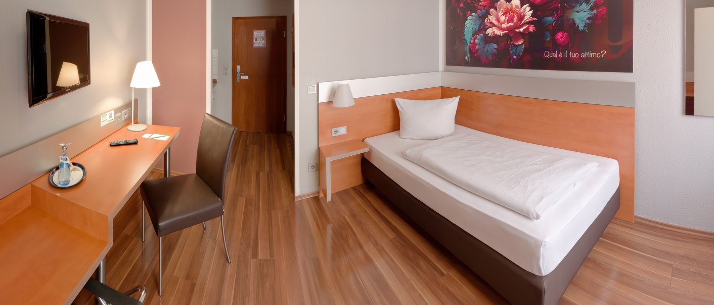 Modernes Einzelzimmer mit Holzboden, Einzelbett, Schreibtisch, Stuhl und großem Blumenbild an der Wand., © attimo Hotel Stuttgart Modernes Einzelzimmer mit Holzboden, Einzelbett, Schreibtisch, Stuhl und großem Blumenbild an der Wand., © attimo Hotel Stuttgart