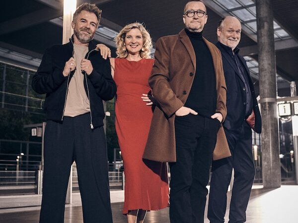 Vier Personen stehen lächelnd in einer modernen Halle. Eine Frau in rotem Kleid und drei Männer in eleganter Kleidung posieren entspannt., © Renitenztheater Stuttgart e.V.