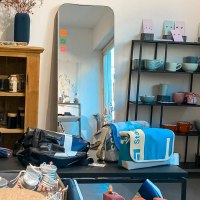 Ein Raum mit Holzschrank, Spiegel, Regalen mit Keramik und Taschen. Fenster mit blauem Licht. Dekorative Elemente auf dem Schrank., © Südstatt, Stuttgart Ein Raum mit Holzschrank, Spiegel, Regalen mit Keramik und Taschen. Fenster mit blauem Licht. Dekorative Elemente auf dem Schrank., © Südstatt, Stuttgart