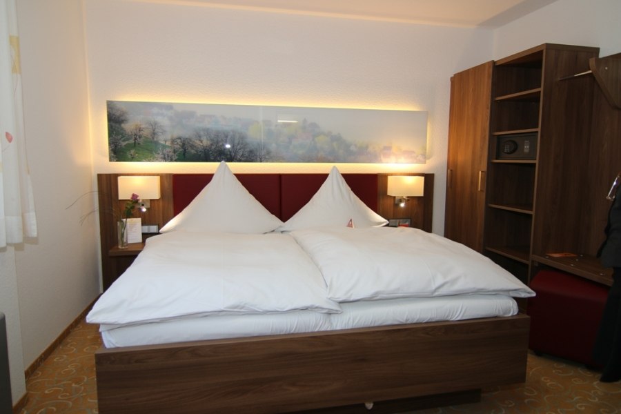 Modernes Doppelzimmer mit großem Bett, Holzschrank und beleuchtetem Wandbild. Dezente Beleuchtung und gemütliche Atmosphäre., © Hotel Gasthof Hasen Modernes Doppelzimmer mit großem Bett, Holzschrank und beleuchtetem Wandbild. Dezente Beleuchtung und gemütliche Atmosphäre., © Hotel Gasthof Hasen
