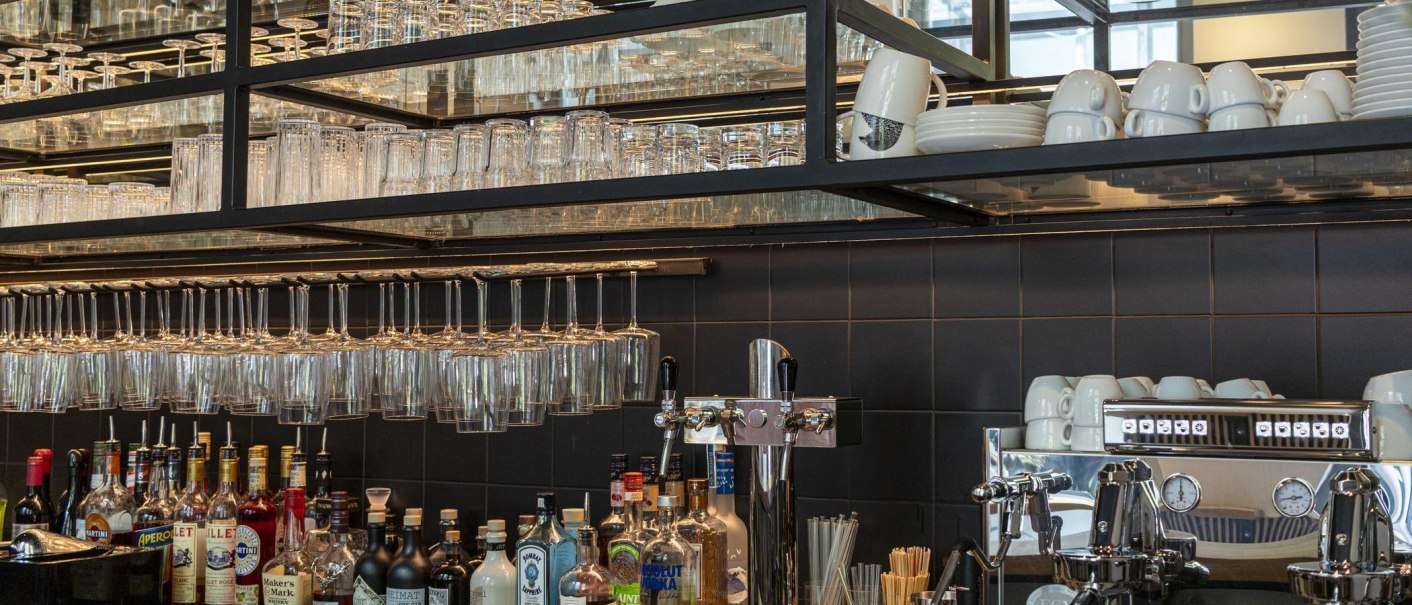 Bar with hanging glasses, bottles of spirits and a coffee machine. Cups and plates are stacked on shelves., © SMG Stuttgart Marketing GmbH - Sarah Schmid