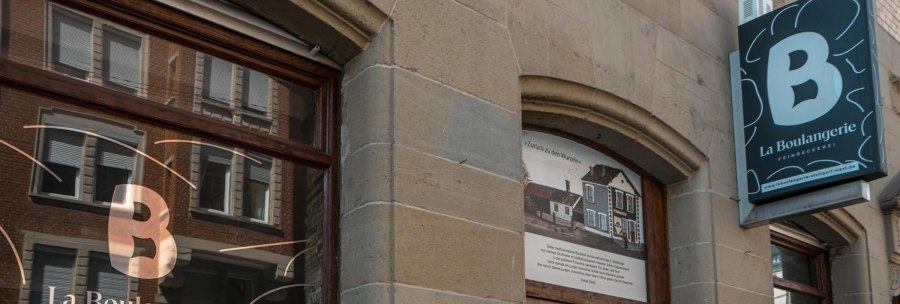 Au&szlig;enansicht der B&auml;ckerei 'La Boulangerie' mit Schaufenster und Schild. Das Geb&auml;ude hat eine steinerne Fassade und spiegelt umliegende Architektur wider., &copy; SMG, Sarah Schmid