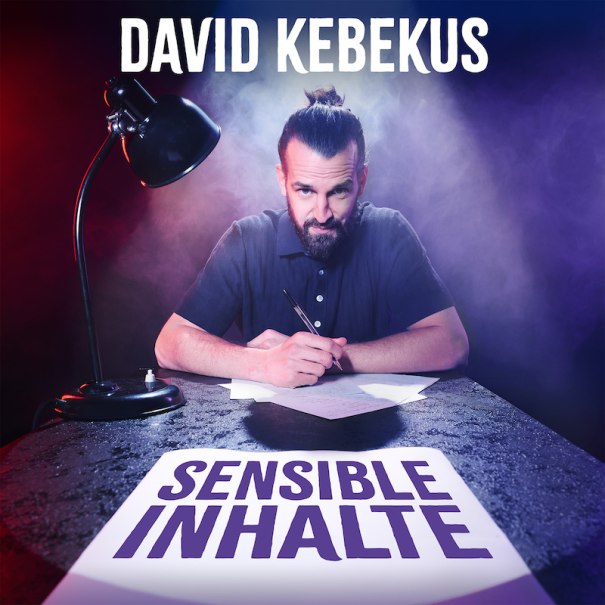 Ein Mann mit Bart und Dutt sitzt an einem Tisch, schreibt auf Papier. Eine Lampe leuchtet ihn an, umgeben von rotem und blauem Licht sowie Rauch., &copy; Rosenau Kultur e.V.