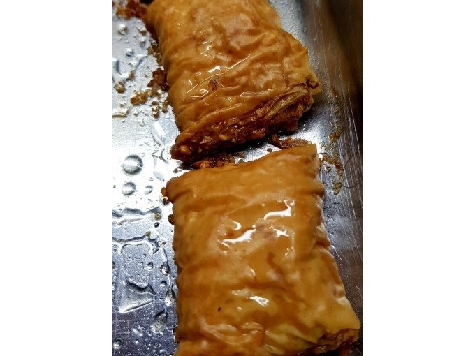 Zwei goldbraune Baklava-Stücke liegen auf einem Blech, glänzend mit Sirup überzogen., © Kultweine-Kochwelten-Kunstücke - Kochschule Sonja Lenz Zwei goldbraune Baklava-Stücke liegen auf einem Blech, glänzend mit Sirup überzogen., © Kultweine-Kochwelten-Kunstücke - Kochschule Sonja Lenz