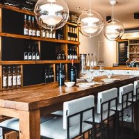 Stilvolle Weinbar mit Holztischen, hohen Stühlen und Weinregalen. Moderne Beleuchtung und gemütliche Atmosphäre., © Stadtbesen! Stilvolle Weinbar mit Holztischen, hohen Stühlen und Weinregalen. Moderne Beleuchtung und gemütliche Atmosphäre., © Stadtbesen!