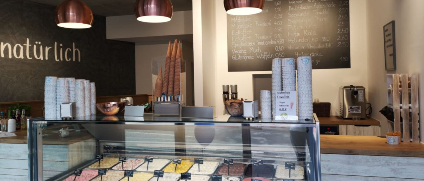 Ice cream parlor with ice cream counter, various types of ice cream, menu board and modern lighting. 'Naturally' lettering on the wall., &copy; Joannis Nakos