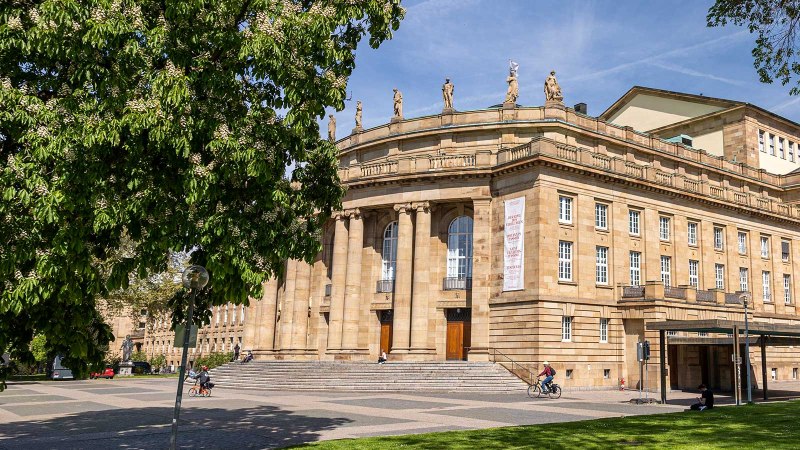 The Stuttgart State Opera in sunny weather, surrounded by green trees and a cyclist in the foreground., © Stuttgart Marketing GmbH, Sarah Schmid The Stuttgart State Opera in sunny weather, surrounded by green trees and a cyclist in the foreground., © Stuttgart Marketing GmbH, Sarah Schmid