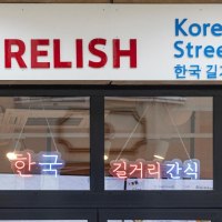 Entrance to a restaurant with the sign 'Relish Korean Street Food' and Korean characters. Neon lights in the window., &copy; Stuttgart-Marketing GmbH, Sarah Schmid