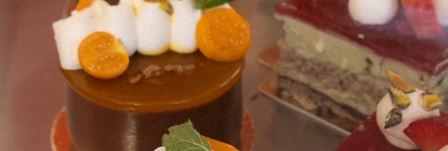 Close-up of artfully decorated cakes in a display case. Various toppings such as fruit and cream can be seen., &copy; SMG