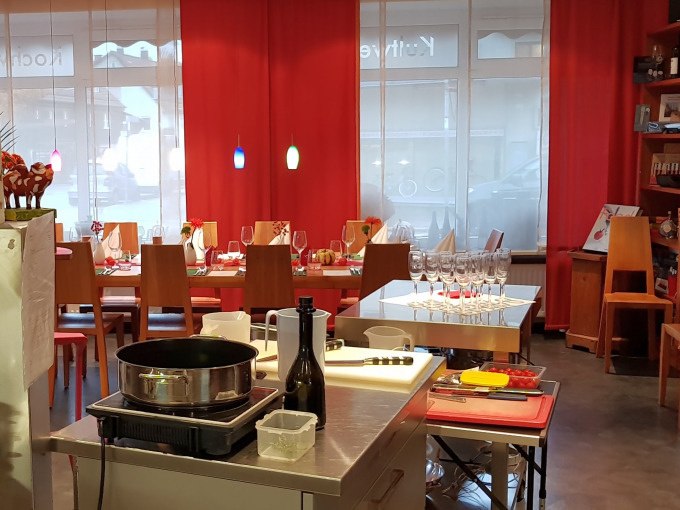 Cooking school with a laid table, cooking utensils and red curtains. Colorful lamps hang from the ceiling., &copy; Kultweine-Kochwelten-Kunst&uuml;cke - Kochschule Sonja Lenz