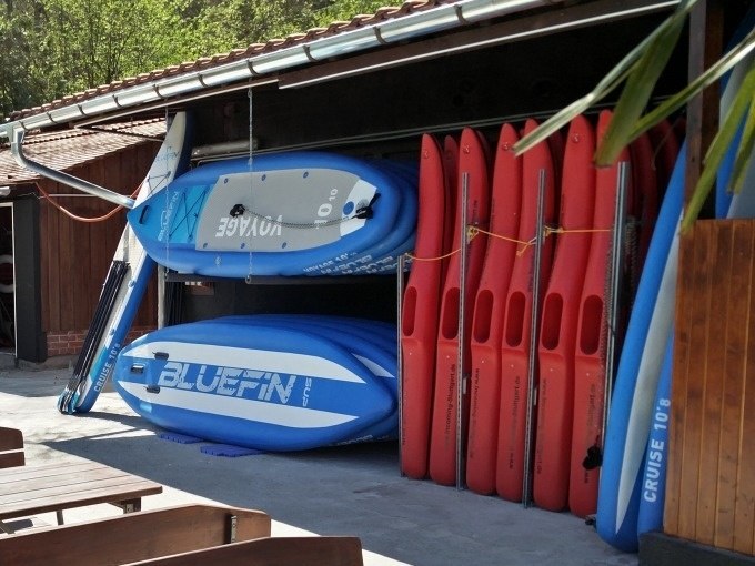 Stacked stand-up paddleboards in an open shed, surrounded by wooden walls and a tiled roof., © Cool-Tours StattReisen Stacked stand-up paddleboards in an open shed, surrounded by wooden walls and a tiled roof., © Cool-Tours StattReisen