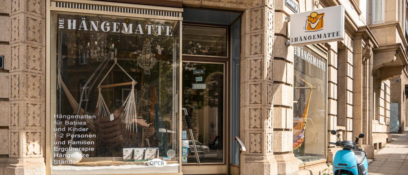 Geschäft 'Die Hängematte' in Stuttgart mit Schaufenster, das Hängematten und Zubehör zeigt. Ein blauer Roller steht davor., © SMG, Sarah Schmid